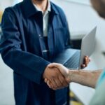 Close-up,Of,Mechanic,Using,Laptop,And,Handshaking,With,Customer,At