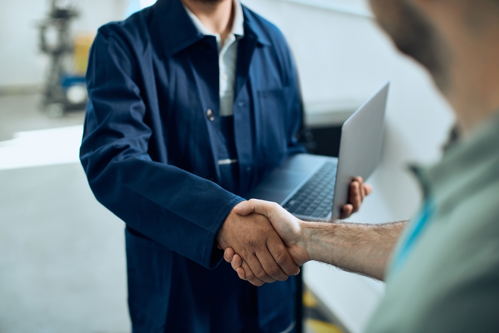 Close-up,Of,Mechanic,Using,Laptop,And,Handshaking,With,Customer,At