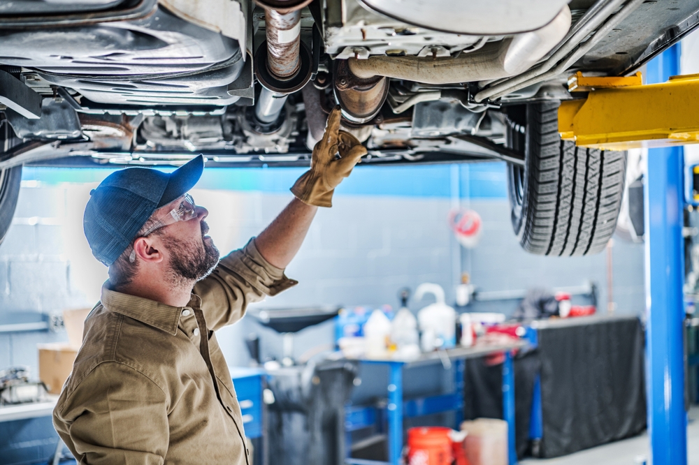 Professional,Caucasian,Mechanic,Standing,Under,The,Vehicle,Lifted,On,Car